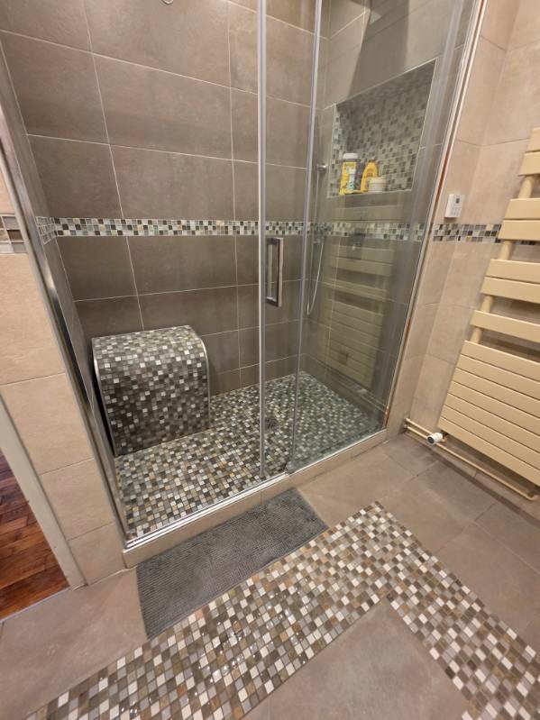 Douche rénovée avec paroi vitrée, assise carrelée et finitions en mosaïque