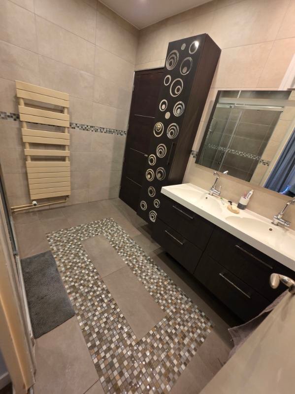 Salle de bain rénovée avec double vasque, meuble sombre, carrelage et mosaïque